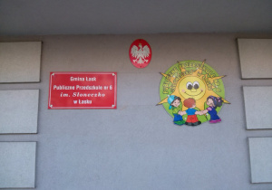 Widok na znajdujący się przed wejściem do przedszkola szyldy z nazwą i logo przedszkola