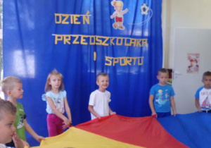 Dzieci trzymające kolorową chustę animacyjną.