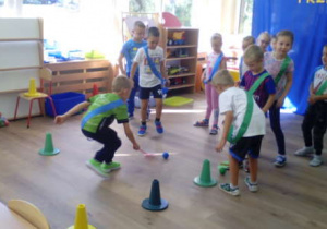 Dwa zespoły dzieci podczas konkurencji -slalom z piłeczką.