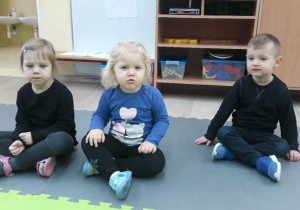 troje dzieci siedzi na macie