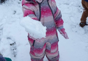 Dziewczynka trzyma kulę śniegową w dłoni