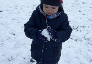 Chłopiec trzyma kulę śniegową w dłoni