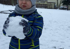 Chłopiec trzyma śniegową kulę