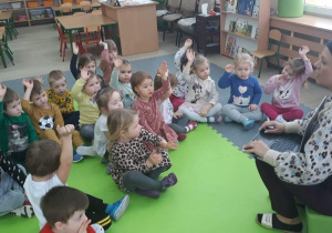 Dzieci trzymają dłonie w górę, zgłaszają się do odpowiedz