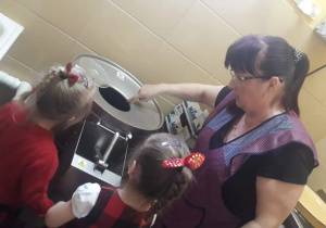 Kobieta pokazuje dzieciom maszynę do obierania ziemniaków
