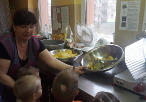 kobieta pokazuje dzieciom praskę do ziemniaków