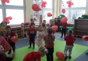 Dzieci trzymają w rękach balony w kolorze czerwonym