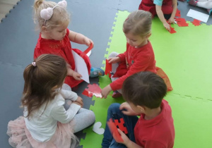 Czworo dzieci układa na macie puzzle w kształcie serca