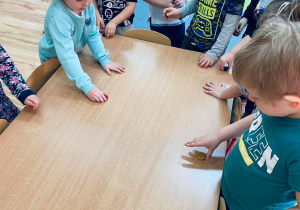 Grupa dzieci sprawdza, czy stolik przyciąga magnesy.