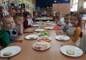Przedszkolaki czekają przy stolikach, by rozpocząć tworzenie wiosennych kanapek.