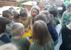 Dzieci stoją wokół żółtego pojemnika