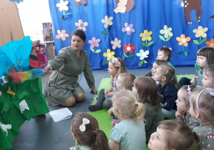 Nauczycielka miotełką przeciera dekorację do przedstawienia, dzieci są wpatrzone w scenografię obserwują