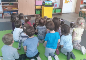 Dzieci siedzą tyłem, oglądają film edukacyjny na ekranie komputera