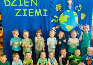 Dzieci ustawione do zdjęcia uśmiechają się i trzymają kciuki w górę.