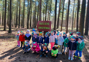 Cała grupa przedszkolaków pozuje do zdjęcia z napisem "Dzień Drzewa".