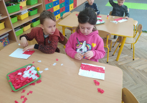 Dzieci wyklejają bibułą biało-czerwoną flagę Polski