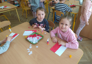 Dzieci wyklejają bibułą biało-czerwoną flagę Polski