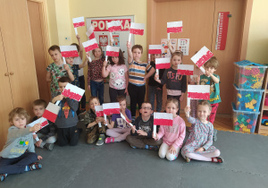 Dzieci pozują do zdjęcia. Każde z nich trzyma w ręku flagę Polski.