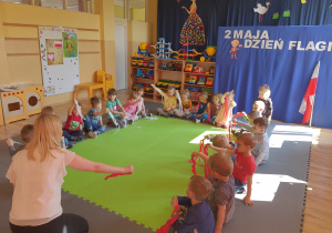 Dzieci wykonują taniec paskami bibuły według instrukcji nauczycielki.