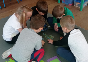 Dzieci siedzą w kole i układają puzzle