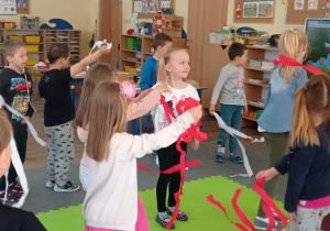 Dzieci tańczą z biało-czerwonymi szarfami