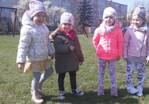 cztery dziewczynki stoją na trawie