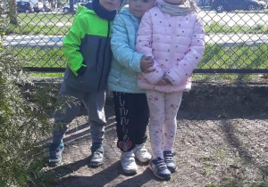Troje dzieci stoi na placu zabaw