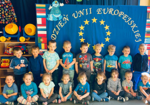 Cała grupa pozuje do zdjęcia na tle dekoracji z okazji Dnia Unii Europejskiej.