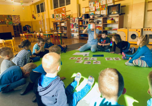 Nauczycielka wraz z dziećmi omawia wygląd flagi Irlandii.