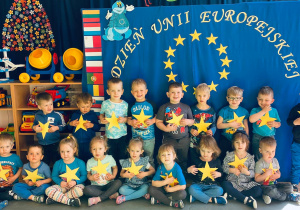 Uśmiechnięte dzieci pozują do zdjęcia trzymając w rączkach żółte gwiazdy.