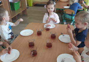 Dzieci siedzą przy stoliku, zjadają podwieczorek