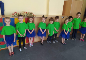 Dzieci w zielono - granatowych strojach recytują tekst "Na jagody"