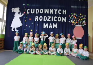 Dzieci pozują do wspólnej fotografii w zielono białych strojach