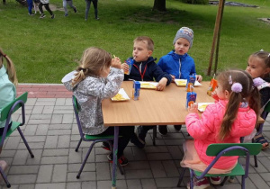 Dzieci jedzą frytki i pija soczki