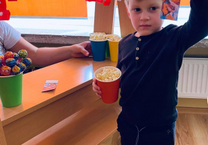 Kubuś pozuje z biletem do kina i popcornem.