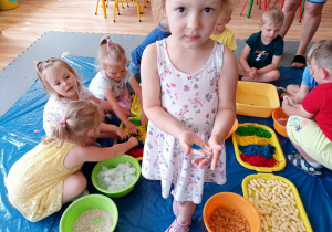 Dzieci bawią się różnymi produktami, Julcia prezentuje do zdjęcia kawałek galaretki.