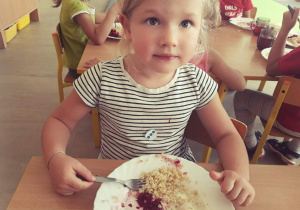 Dziewczynka zjada kropkową kaszę z talerza