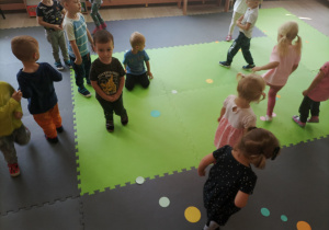 Dzieci spacerują po sali, w poszukiwaniach rozsypanych kropek.