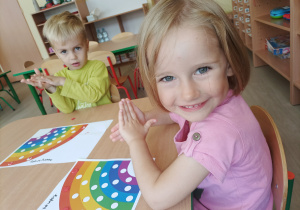 Dziewczynka i chłopiec tworzą kulki z kolorowej plasteliny.