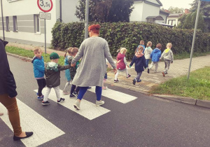 Dzieci przechodzą przez jezdnię po pasach
