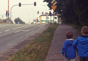 Dzieci idą w kierunku przejścia dla pieszych z sygnalizacją świetlną