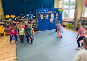Dzieci tańczą trzymając balony pomiędzy nogami.