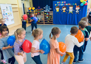 Dzieci tworzą pociąg z balonami.