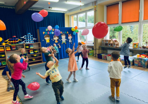 Dzieci swobodnie odbijają kolorowe balony.