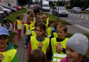 Dzieci poruszają się parami po chodniku w pobliżu ulicy.