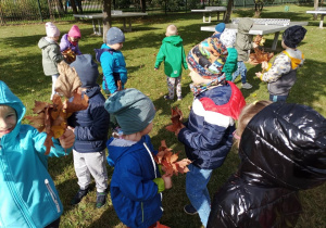Przedszkolaki zbierają i oglądają jesienne liście.