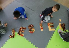 chłopcy układają napis jesień z darów natury