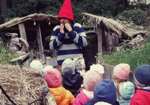 Mężczyzna w czerwonej czapce skrzata mówi do dzieci