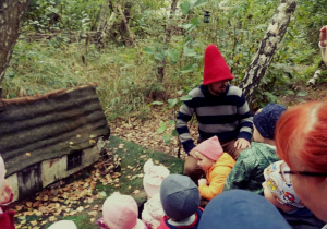 Dzieci kucaja przy miniaturze domku Skrzatow