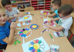 Dzieci kolorują kwiaty i jedzą lizaki.